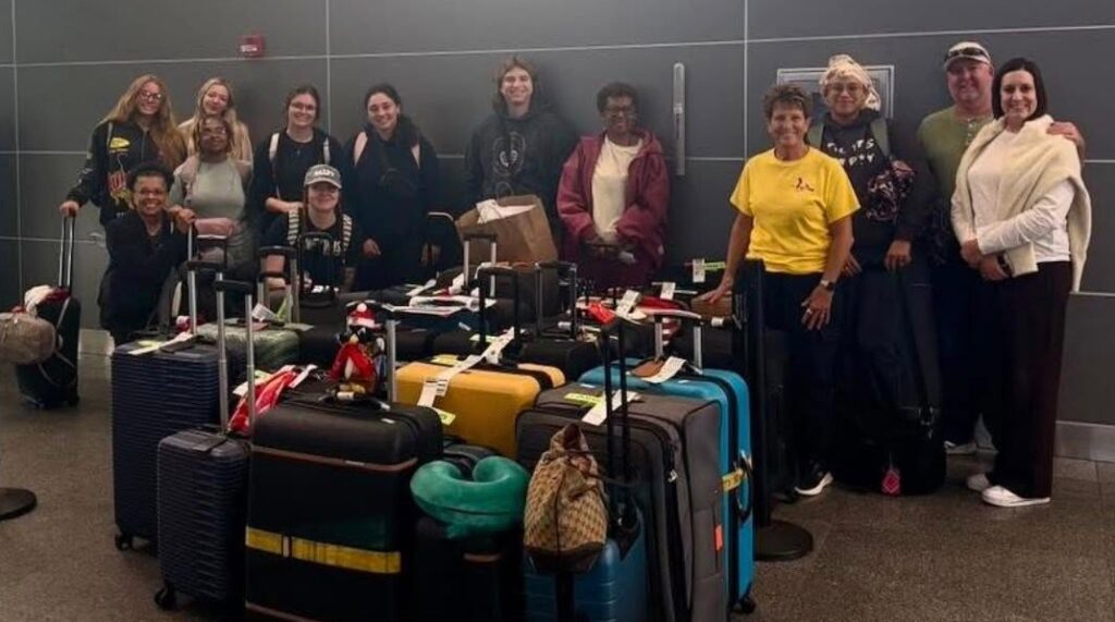 Students, faculty and alumni with suitcases in the airport.