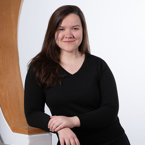 Portrait of Master of Music in Music Performance student, Jessyka Martins. She's wearing a black shirt and pants, leaning on a railing inside the McDonough Museum of Art on YSU's campus.