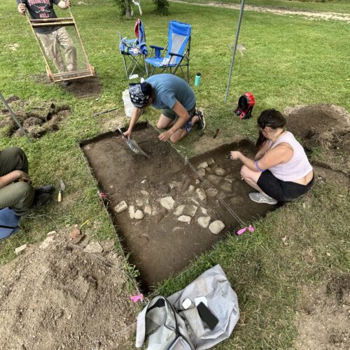 YSU anthropology students and volunteer uncovering feature in the ground
