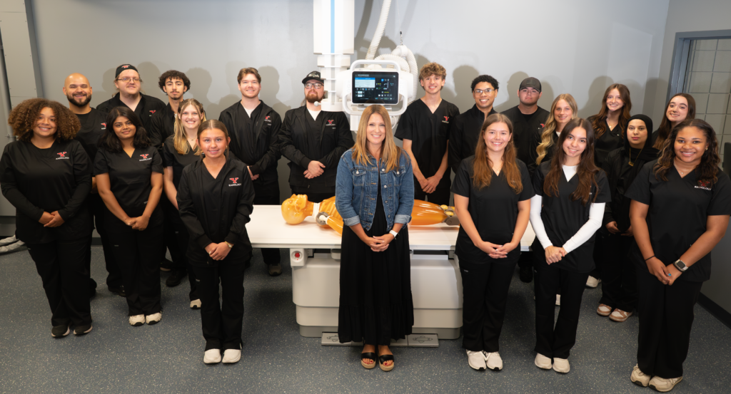 YSU Radiologic Technology students in a lab with medical imaging equipment and a training mannequin.
