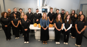 YSU Radiologic Technology students in a lab with medical imaging equipment and a training mannequin.