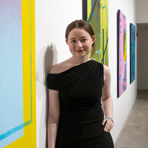 Interdisciplinary Art graduate, Lauren Barrett, standing in front of her artwork during the Spring 2026 Graduating BFA Exhibition